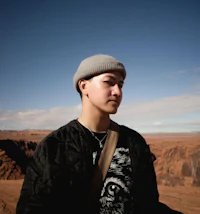 a young man in a beanie standing in a desert